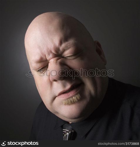 Caucasian mid adult bald man squinting and making facial expression.