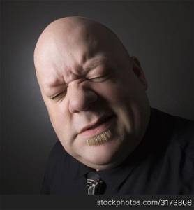 Caucasian mid adult bald man squinting and making facial expression.