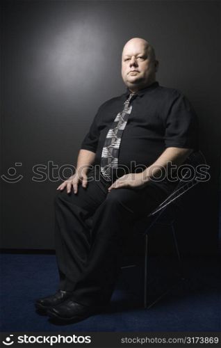 Caucasian mid adult bald man wearing necktie sitting and looking at viewer.