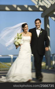 Caucasian mid-adult bride and groom walking together smiling.