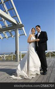 Caucasian mid-adult bride and groom wedding portrait outside at beach.