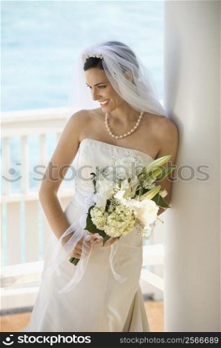 Caucasian mid-adult bride holding bouquet looking down.