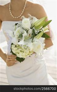 Caucasian mid-adult bride holding flower bouquet.