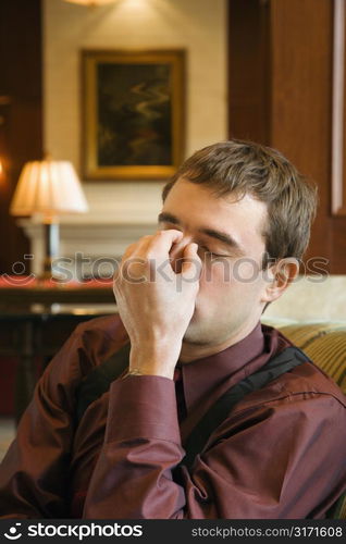 Caucasian mid adult buisinessman holding forehead with eyes closed.