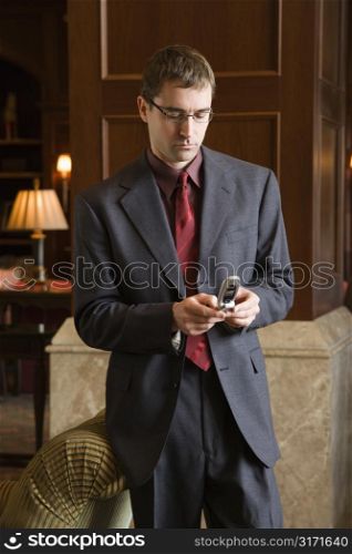 Caucasian mid adult buisinessman looking down at cell phone.