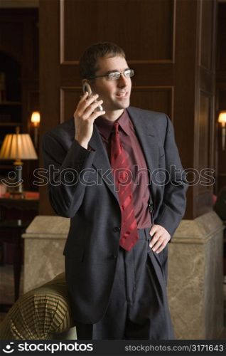 Caucasian mid adult buisinessman on cell phone with hand on hip.