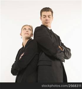 Caucasian mid-adult businessman and woman standing back to back looking at each other.
