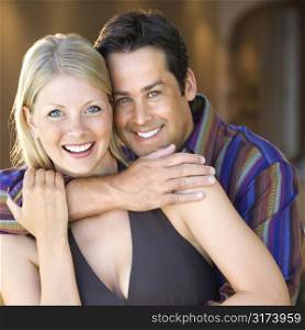 Caucasian mid adult couple embracing and smiling at viewer.