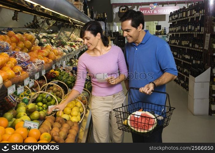 Caucasian mid-adult couple grocery shopping for fruit.