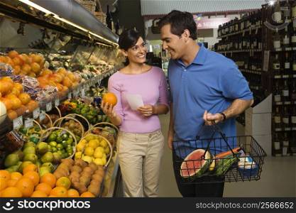 Caucasian mid-adult couple grocery shopping for fruit.