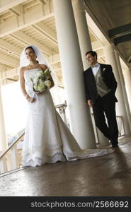 Caucasian mid-adult fbride and groom standing on porch.