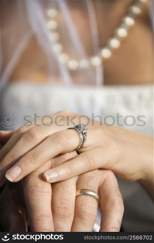 Caucasian mid-adult male and female hands with wedding rings.
