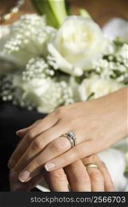 Caucasian mid-adult male and female hands with wedding rings.