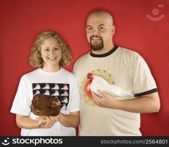 Caucasian mid-adult male and female holding chickens.