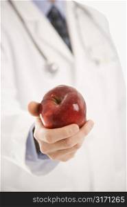 Caucasian mid adult male physician holding apple.