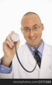 Caucasian mid adult male physician holding up end of stethescope.