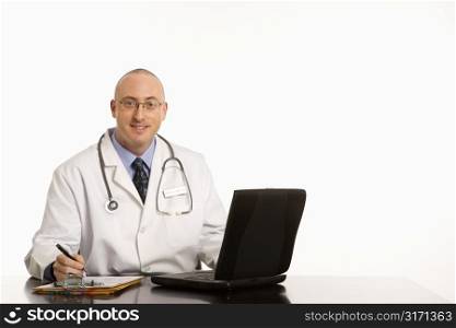 Caucasian mid adult male physician sitting at desk with laptop computer.