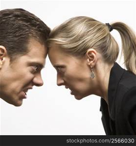 Caucasian mid-adult man and woman with foreheads together staring at each other with hostile expressions.