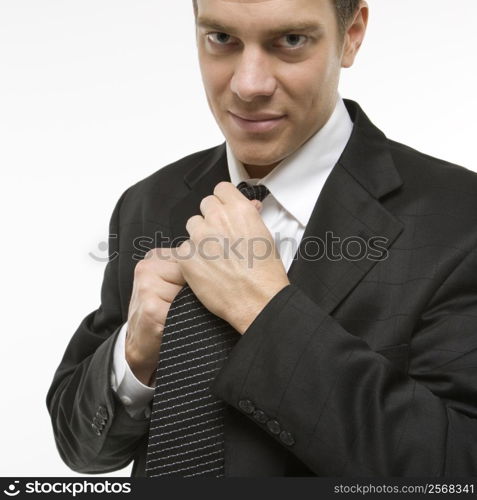 Caucasian mid-adult man straightening necktie.