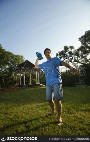 Caucasian mid-adult man throwing football.
