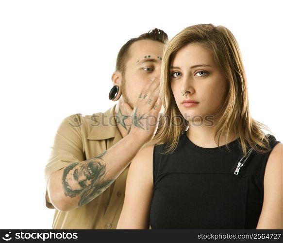 Caucasian mid-adult man whispering into ear of teen female.