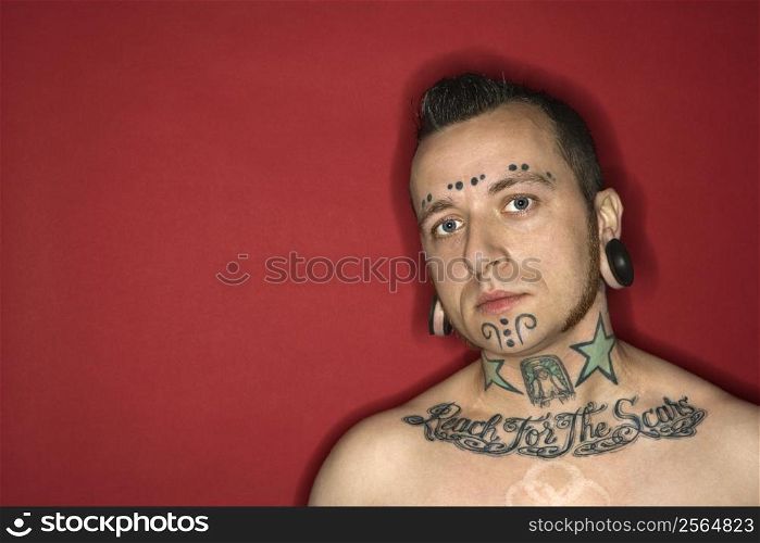 Caucasian mid-adult man with tattoos and piercings.