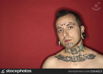 Caucasian mid-adult man with tattoos and piercings.