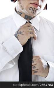 Caucasian mid-adult man with tattoos and piercings adjusting necktie.