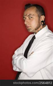 Caucasian mid-adult man with tattoos and piercings wearing necktie looking at viewer.