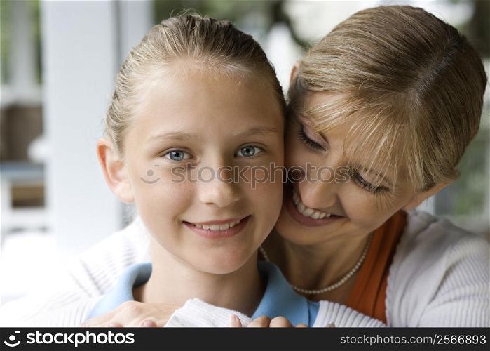 Caucasian mid-adult mother hugging pre-teen daughter.