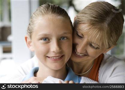 Caucasian mid-adult mother hugging pre-teen daughter.