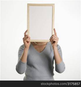 Caucasian mid adult professional business woman holding up blank dry erase board in front of her face.