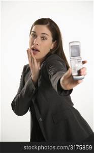 Caucasian mid adult professional business woman taking picture of self with camera phone with hand on chin.