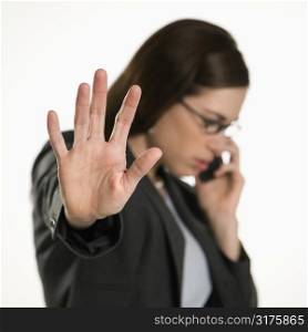 Caucasian mid adult professional business woman talking on cell phone holding hand out to stop viewer.