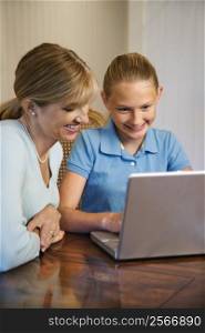 Caucasian mid-adult woman and pre-teen girl using laptop computer.
