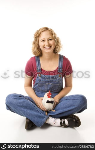 Caucasian mid-adult woman holding Old English Bantam Rooster wearing bow tie.