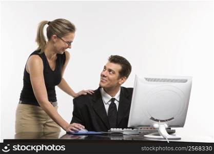 Caucasian mid-adult woman touching mid-adult man&acute;s shoulder and using mouse at computer.