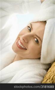 Caucasian mid-adult woman wearing towel on head smiling at viewer.