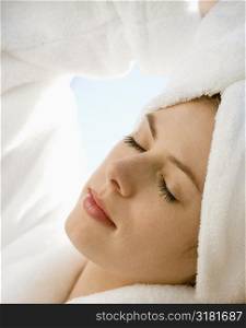 Caucasian mid-adult woman wearing towel on head with eyes closed relaxing.