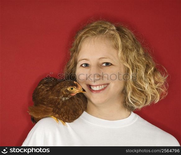 Caucasian mid-adult woman with chicken on shoulder.