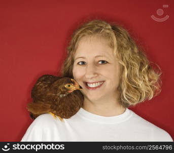 Caucasian mid-adult woman with chicken on shoulder.