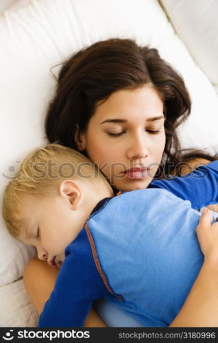 Caucasian mid adult woman with toddler son sleeping in bed.