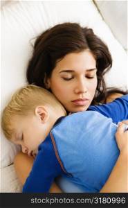 Caucasian mid adult woman with toddler son sleeping in bed.