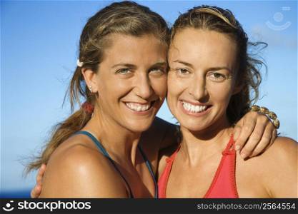 Caucasian mid-adult women holding each other smiling.