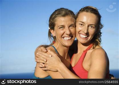 Caucasian mid-adult women hugging each other smiling.
