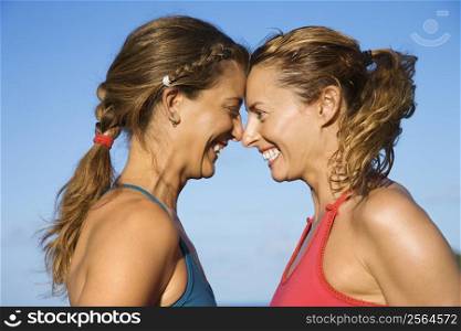 Caucasian mid-adult women with heads together smiling.