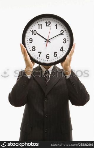 Caucasian middle-aged businessman holding clocks in front of their heads standing against white background.