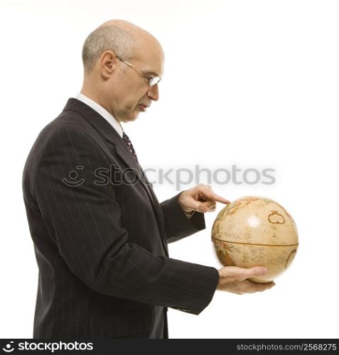 Caucasian middle-aged businessman holding globe and pointing standing in front of white background.