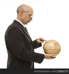 Caucasian middle-aged businessman holding globe and pointing standing in front of white background.