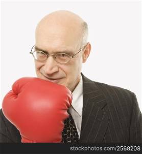 Caucasian middle-aged businessman holding up arm wearing boxing glove.